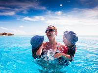 Happy family splashing in blue swimming pool on a tropical resort