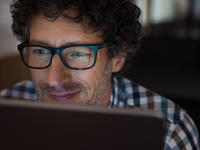 Man with glasses, looking at his computer screen