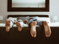 Feet of two people lying on a bed